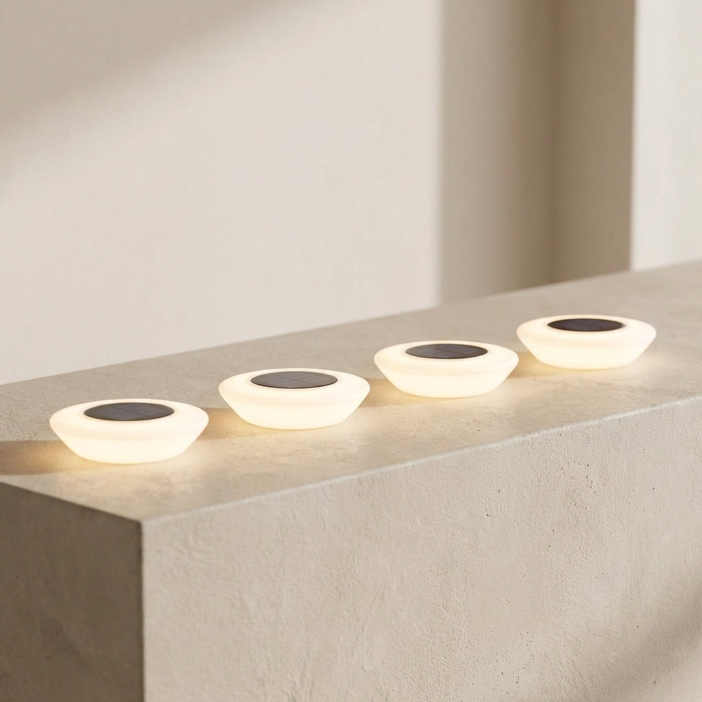 Four modern outdoor lights on a concrete surface with a neutral background