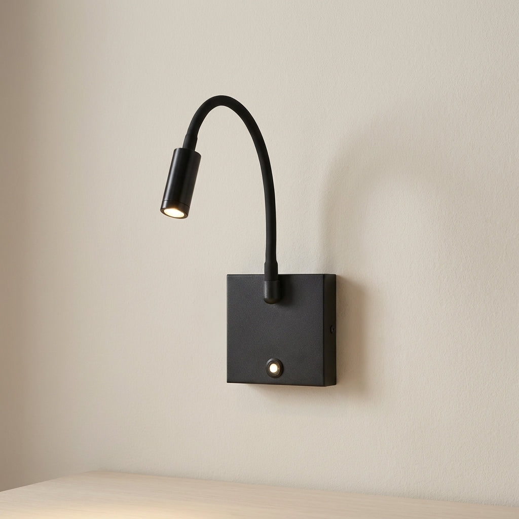 Modern black wall-mounted reading light on a beige wall
