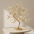 Decorative gold tree with lights on a white surface against a beige background