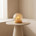 Decorative glass lamp on a small round table with a neutral background