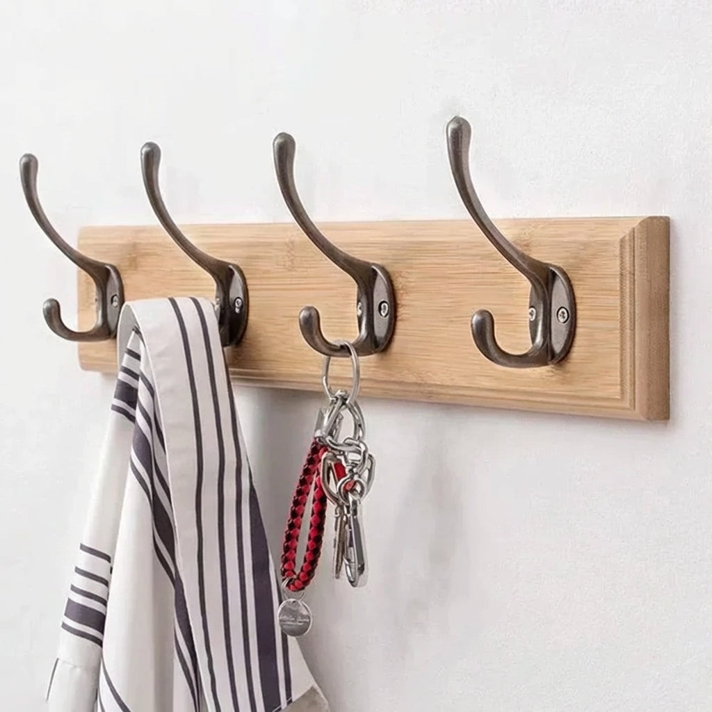 Wooden wall hook with four metal hooks holding a striped towel and keys on a white background