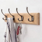 Wooden wall hook with four metal hooks holding a striped towel and keys on a white background