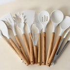 Set of white kitchen utensils with wooden handles on a beige background