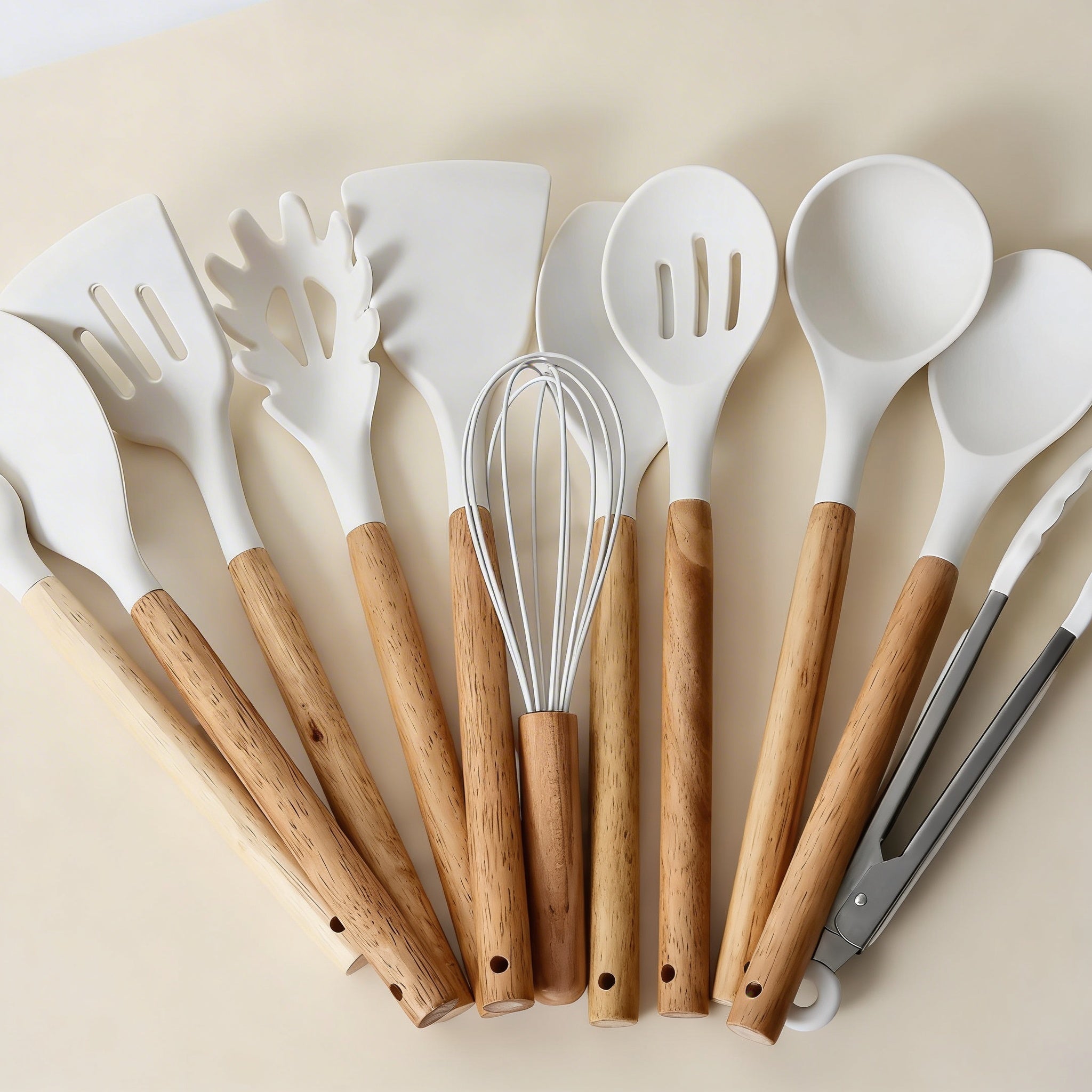Set of white kitchen utensils with wooden handles on a beige background