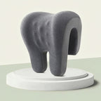 Gray abstract sculpture on a white platform against a light green background
