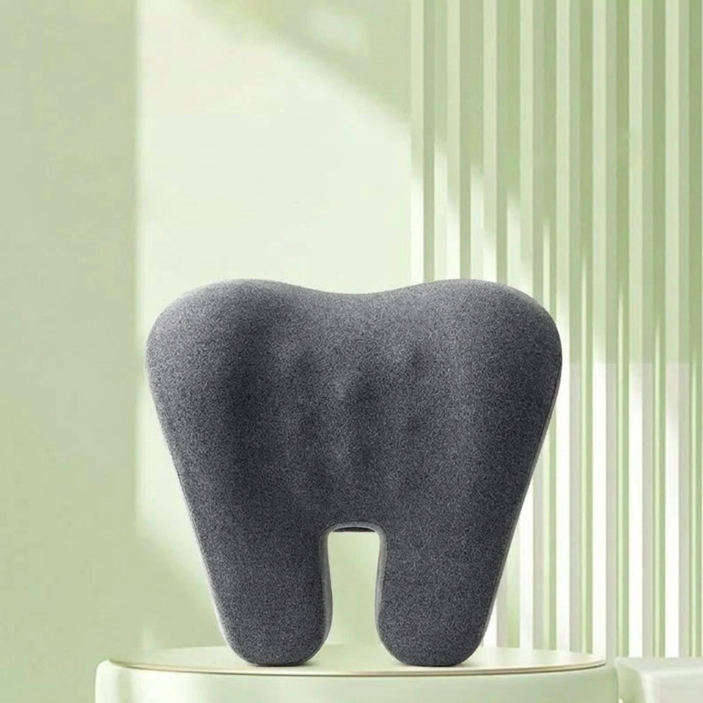 Gray tooth-shaped pillow on a white surface with a light green curtain background