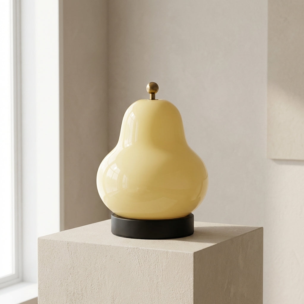 Yellow pear-shaped lamp on a pedestal against a neutral wall