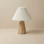 Table lamp with pleated white shade and wicker base on a beige background