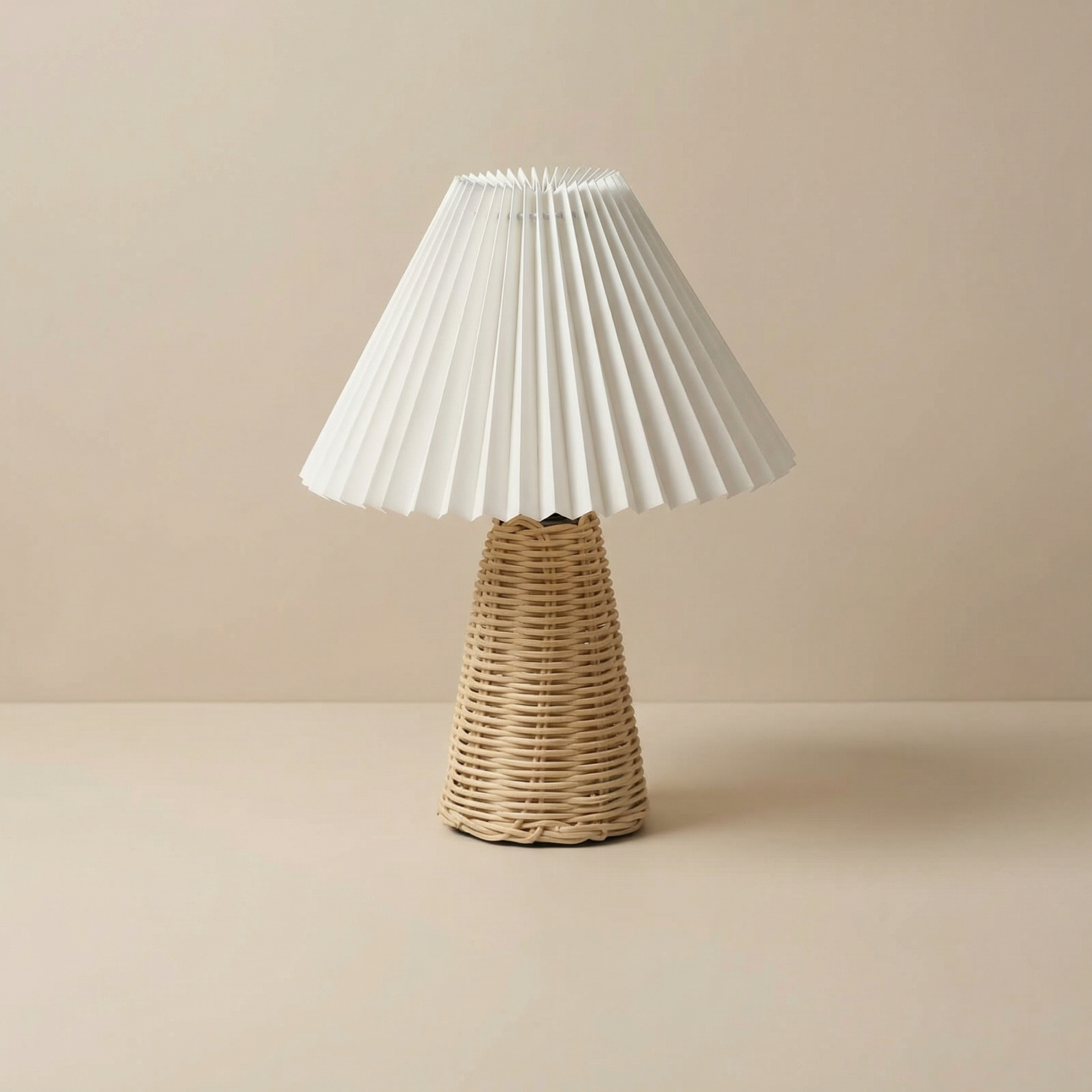 Table lamp with pleated white shade and wicker base on a beige background