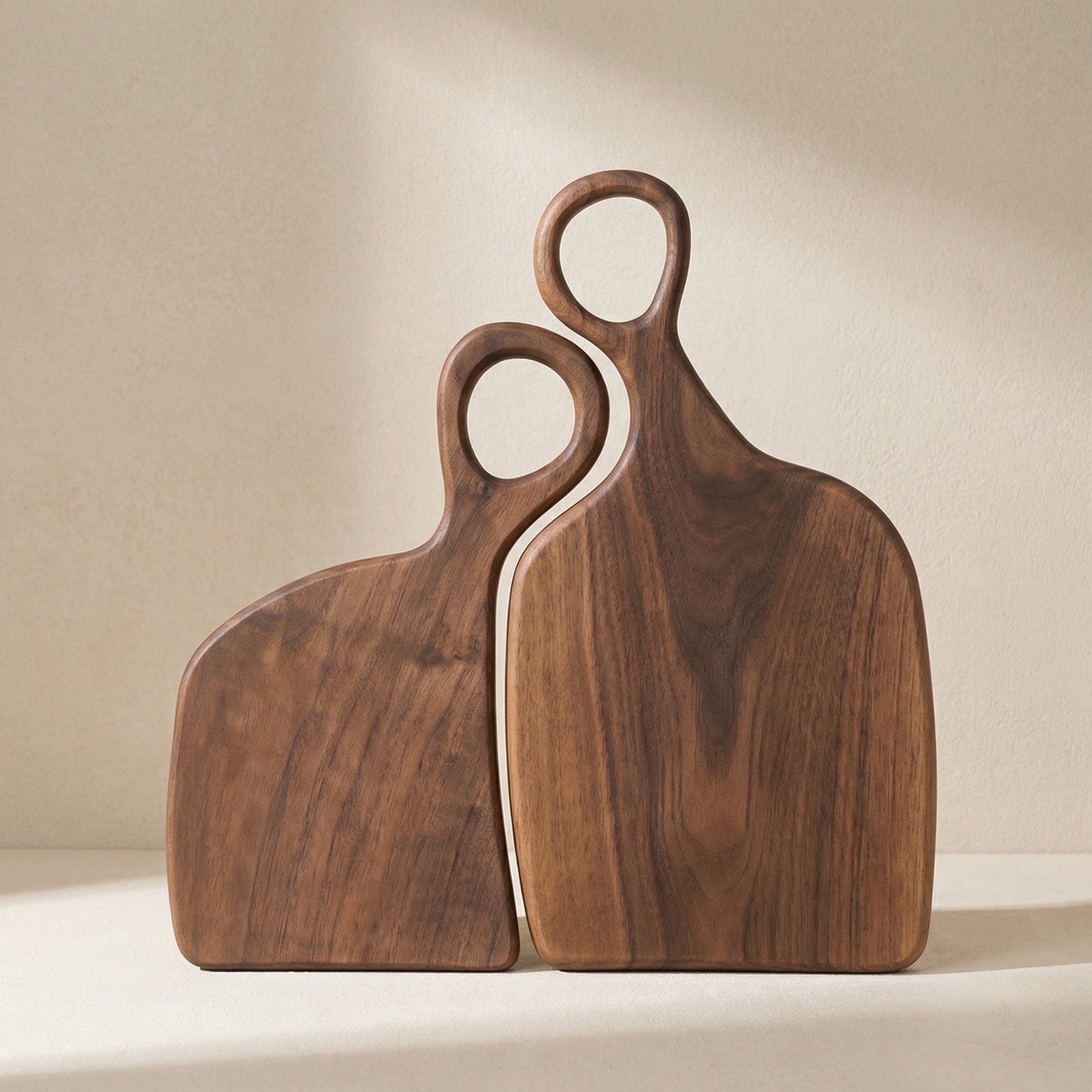 Two wooden cutting boards with handles on a beige background
