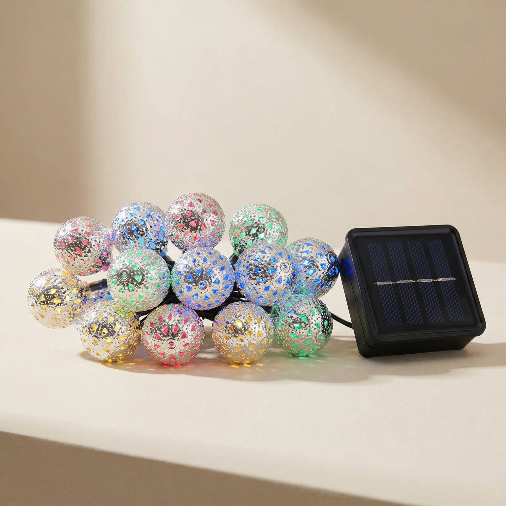 Decorative string lights with colorful glittery balls and a solar panel on a beige background