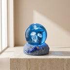 Decorative glass ball with jellyfish inside on a stone surface