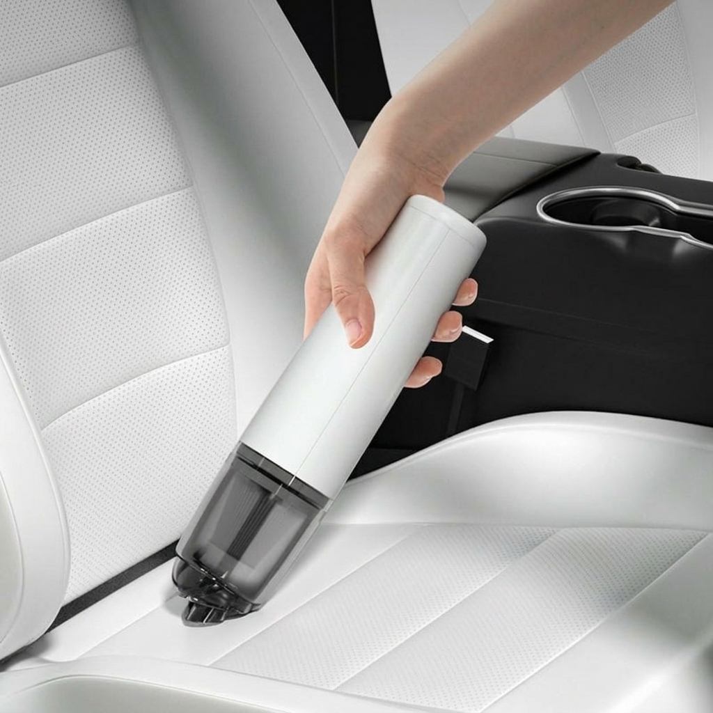 Hand holding a white handheld vacuum cleaner on a car seat