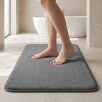 Person stepping onto a gray bath mat in a bathroom setting