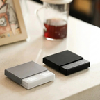 Two electronic devices, one gray and one black, on a surface with a blurred background.