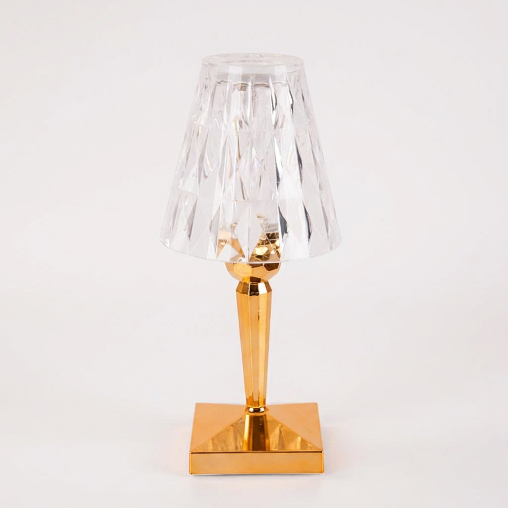 Table lamp with gold base and clear glass shade on a white background