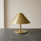Gold table lamp on a gray surface with a neutral background