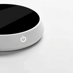 Round black and white device with power symbol on a light gray background