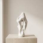 Abstract white sculpture on a beige pedestal against a plain background