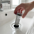 Hand installing a decorative drain cover into a sink drain.