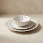Set of white ceramic bowls and plates on a beige surface