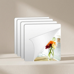Set of four square mirror coasters on a beige surface with a blurred background