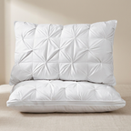 Two white quilted pillows on a beige surface with a neutral background
