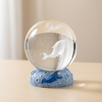 Decorative glass ball with a dolphin design on a beige background