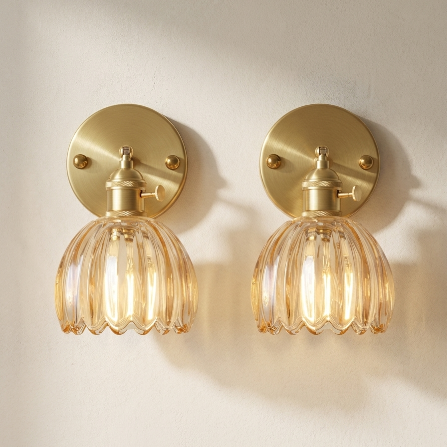 Two gold wall sconces with clear glass shades on a light beige wall.