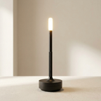 Modern black table lamp with a lit bulb on a neutral background