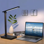 Black desk lamp on a wooden surface with a laptop displaying a scenic wallpaper.