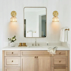 Bathroom vanity with wooden cabinets, mirror, and gold sconces.