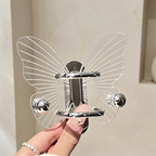 Butterfly-shaped hair clip held by a hand against a neutral background