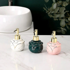 Three ceramic soap dispensers with marble patterns in white, green, and pink on a marble surface.