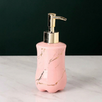 Pink marble-patterned soap dispenser with gold accents on a white surface.