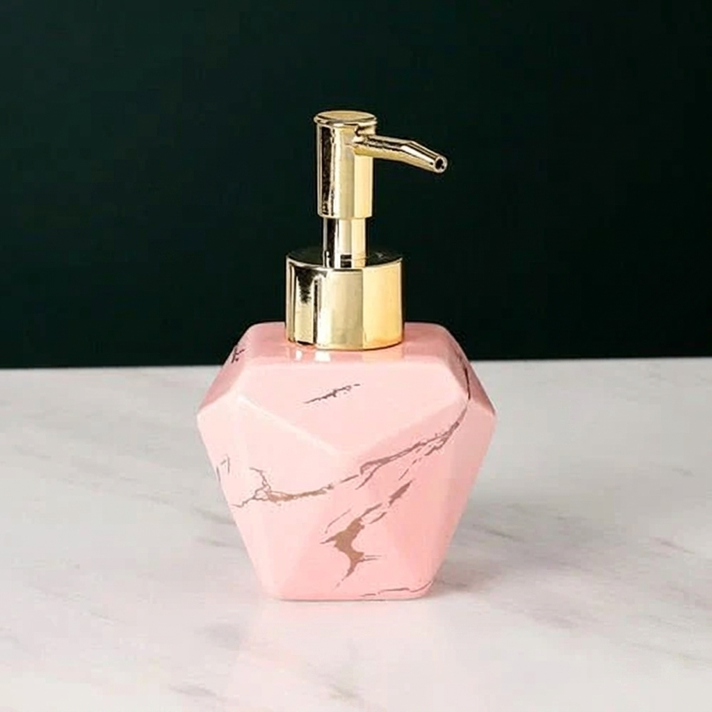 Pink marble-patterned soap dispenser with gold pump on a white surface
