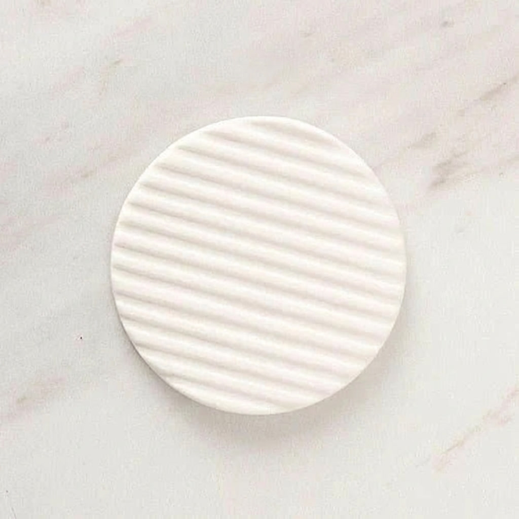 White ceramic plate with ribbed texture on a marble surface