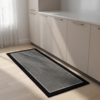 Long rectangular rug with black border on a wooden floor in a kitchen setting.