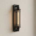 Black wall-mounted light fixture with glass cover on a beige wall