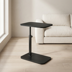 Black adjustable side table in a living room setting with a beige sofa and light wood flooring.