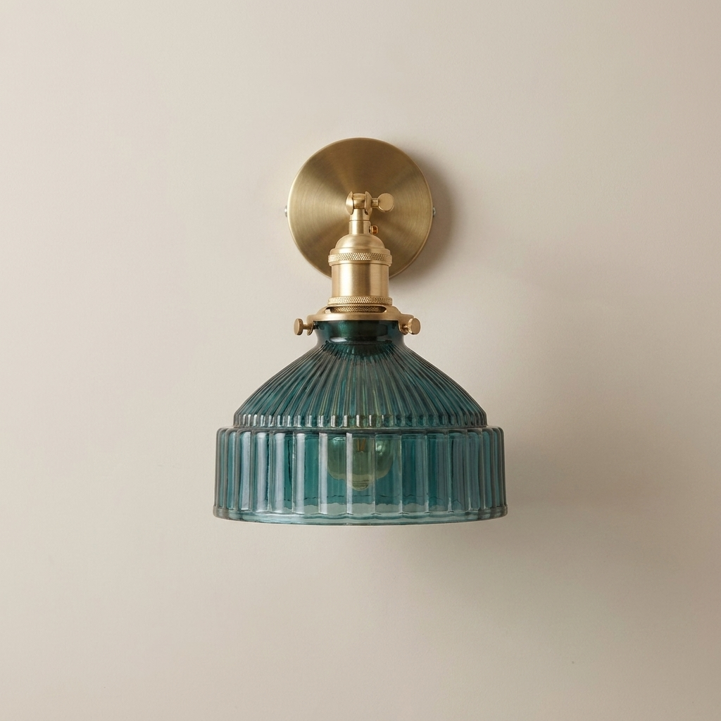 Wall-mounted light fixture with brass fitting and ribbed teal glass shade on a beige background