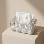 Clear glass egg carton with a white napkin on a beige surface
