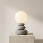 Modern table lamp with a stack of gray ceramic bases on a neutral background