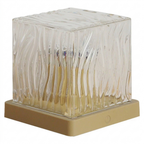 Square glass candle holder with wavy design on a beige base