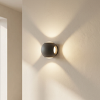 Modern wall-mounted light fixture casting a soft glow on a neutral wall.