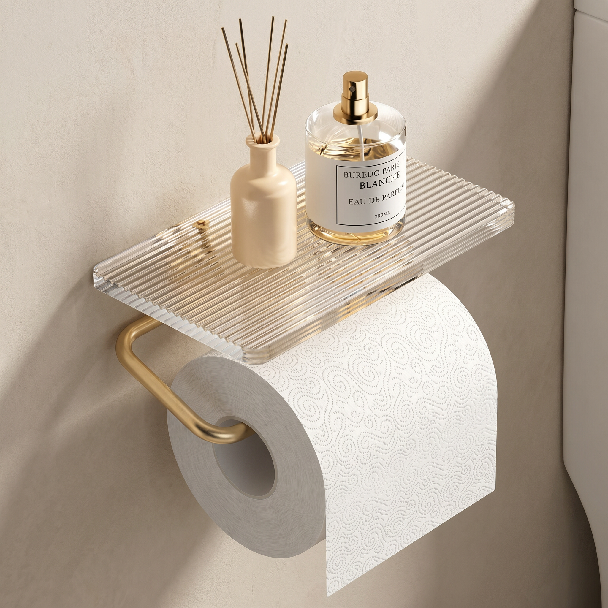 Clear acrylic shelf with gold accents holding a roll of toilet paper, a diffuser, and a perfume bottle against a beige wall.