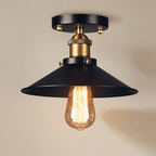 Ceiling light fixture with a black shade and exposed bulb on a beige background