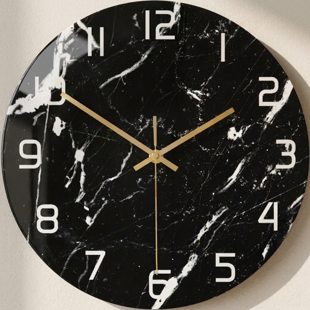 Black marble-patterned wall clock with gold hands on a light gray background