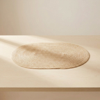 Round woven mat on a wooden surface with a neutral background
