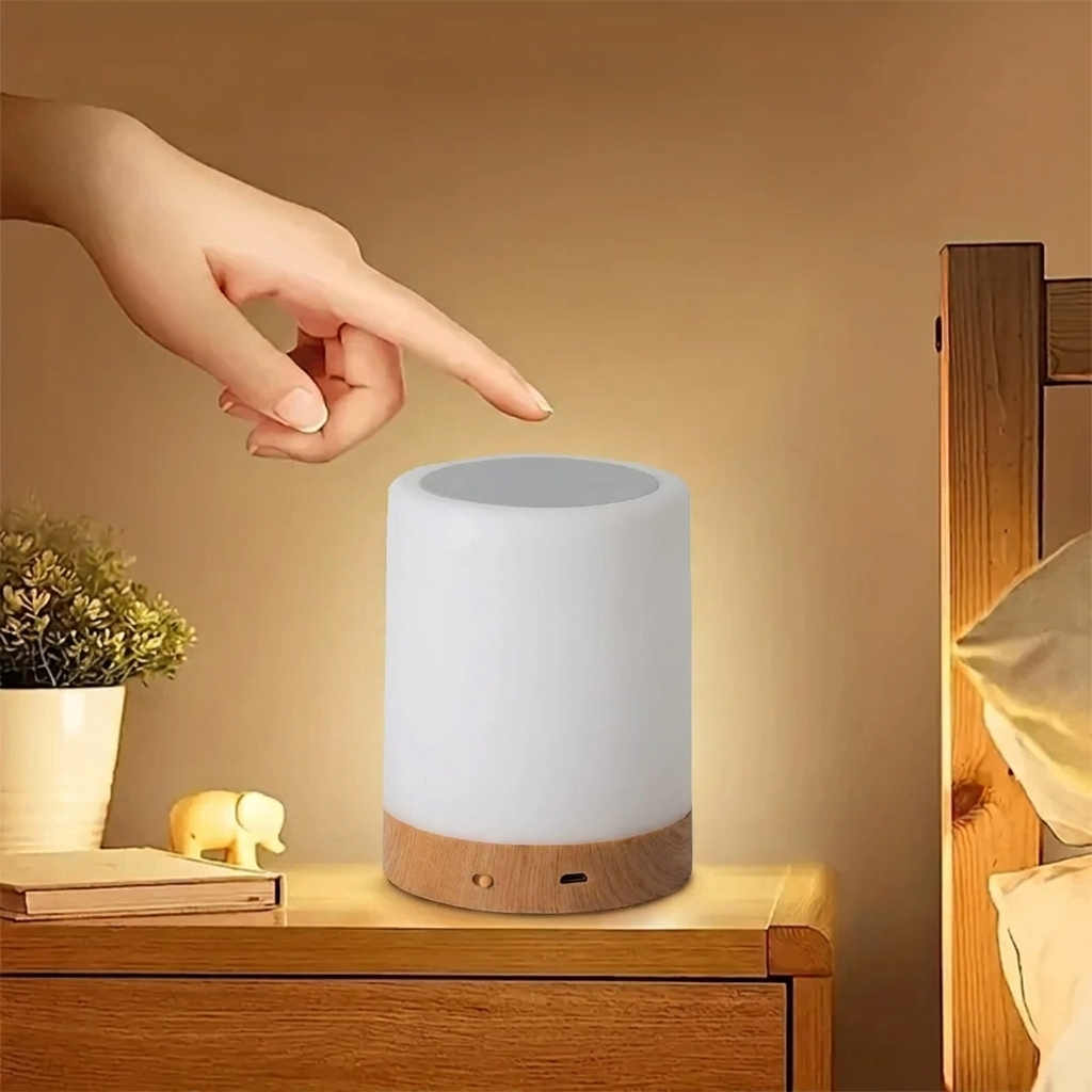 Hand touching a white night light on a wooden nightstand with a warm glow.